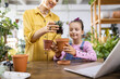 © sofiko14 - A woman and a young girl are repotting a succulent plant in a bright, indoor setting