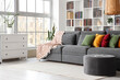 © Pixel-Shot - Interior of living room with pouf, sofa and book shelf near white wall