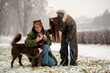 © Cavan Images - mother and teenage daughter play with their dog in a snowy park.