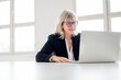 © Westend61 - Smiling mature businesswoman working on laptop at desk in the office