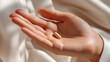 © PhotoLuxeStudio - Asian woman open palm holding single beige capsule with soft light on skin, health and wellness concept
