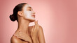 © Home-stock - Face mask, skincare concept. Young European lady with cosmetics, posing over pink background, enjoying spa treatments