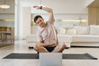 © muse studio - Man stretches at home while following an online exercise session in the morning