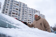 © phpetrunina14 - Man Clearing Snow from Car in Winter Cityscape Copy Space