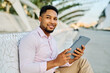 © Lumos sp - Portrait of a young  businessman wman using a tablet computer  in a city park, surrounded by modern corporate office buildings architecture