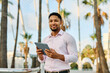 © Lumos sp - Portrait of a young  businessman wman using a tablet computer  in a city park, surrounded by modern corporate office buildings architecture