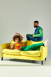 © LIGHTFIELD STUDIOS - Stylish young friends enjoying a fun moment on a vibrant yellow couch in modern attire