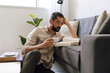 © kleberpicui - Adult man enjoying coffee while reading book at home. Quiet break moment highlighting relaxation, focus and balanced lifestyle inside bright modern living room.
