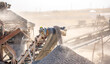© Vera - Vibrating screen stone crusher in operation. Crushing stones in a quarry for processing minerals, cement, limestone. Heavy and mobile equipment in a quarry for processing stone into building material.