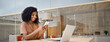 © insta_photos - Happy young African American business woman holding smartphone sitting in office, smiling ethnic businesswoman using financial banking app on cell phone looking at cellphone working with mobile tech.