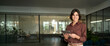 © insta_photos - Smiling young Hispanic professional business woman using tablet standing in office. Happy businesswoman manager, female executive leader holding tab at work, looking at camera. Portrait.