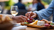 © Kateryna - Faceless woman's hand reaching across table to pick a grape from a shared charcuterie board at outdoor cafe social dining sharing food culture female friendship concept