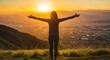 © florynstudio3 - Woman with arms outstretched on a mountaintop embraces a brilliant sunset over cityscape
