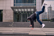 © Nano - A young adult dances hip hop breakdance, jumping and dancing enthusiastically in the streets. He wears comfortable clothes and exudes attitude, movement, and positive energy. Street dance, freestyle