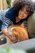 © mahalo studio/Stocksy - woman cuddling with shiba inu dog on sofa