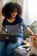 © mahalo studio/Stocksy - Woman working from home with pet dog