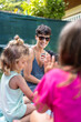 © Alvaro Lavin/Stocksy - Mother smiling with her three daughters while relaxing in garden
