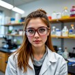 © Cherrisa - Young female scientist with glasses in a laboratory surrounded by scientific equipment.