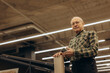 © Roman - Senior man working in warehouse holding phone