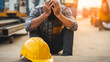 © photo for everything - Stressed construction worker experiences burnout at industrial site, head in hands, with yellow hardhat on ground, highlighting work pressure