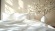 © bright - Serene sunlit bedroom with rumpled white bedding, two pillows and a vase of delicate blossoming branches on a bedside table conveying calm morning peace