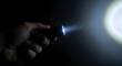 © Sanur - Person holding a small flashlight illuminating a bright light beam in the darkness with a soft halo effect on the right side