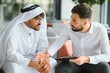 © Serhii - International operations manager meeting saudi business partner wearing traditional kandura