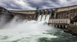 © Wisnu - Powerful hydroelectric dam releasing torrents of water, a grand display of sustainable energy generation and vital industrial engineering, under a dramatic cloudy sky