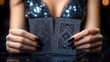 © video - Close-up of woman's hands with long black nails holding two ornate black playing cards over a reflective glossy table, glittering sequin dress and blurred cleavage evoking mystery and seduction