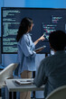© SAT65 - Asian Female Developer presenting code to Colleagues or Team Explaining code and discussing on software development task during code meeting or software training, Cybersecurity in office at night.