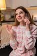 © Andrii Iemelianenko - Middle-aged woman at night home talks on smartphone active call smiles enjoys conversation friendly tone. Caucasian girl on sofa at evening listens responds laughs chat social connection happy mood.