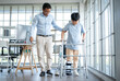 © Wosunan - Father assisting young boy during physical therapy session using a walker in hospital