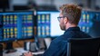 © Nitchalee N. - Electronic tax system, A man with glasses works focused at a desk in front of multiple monitors displaying colorful data and charts in a modern office setting.