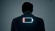 © vectyx2 - Businessman silhouette displaying a low battery icon glowing on his back symbolizing extreme exhaustion and need for energy recharge
