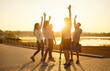 © Studio Romantic - Runners celebrate end of morning marathon challenge with hands up and happy laughter. Group of fit people stretching by lake at sunrise, celebration of teamwork, fitness goals and unity of athletes
