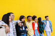 © Xavier Lorenzo - Group of cheerful young students enjoying time together, embracing and laughing against a vibrant yellow wall, representing diversity, friendship, and youthful joy