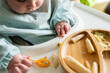 © Raul Navarro/Stocksy - Baby eating solid food wearing bib in high chair