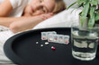 © brizmaker - Woman sleeps in bed with prescribed medication and glass of water nearby