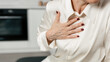 © brizmaker - A mature woman feels chest pain while seated in her living room