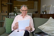 © Rowena Naylor/Stocksy - Elderly man reads documents in modern living room during daytime