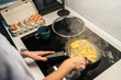 © Alvaro Lavin/Stocksy - Woman cooking scrambled eggs in modern kitchen in Spain