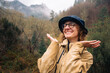 © Maria Sher/Stocksy - Smiling woman embracing the rain in a misty mountain landscape