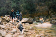 © Maria Sher/Stocksy - Group hiking in a rocky landscape with a stream
