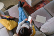 © Jesse Morrow/Stocksy - Top down woman on couch holding phone
