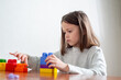 © Olena Smyrnova/Stocksy - child with autism lines up colorful toy blocks