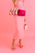 © Tania Cervian/Stocksy - Unrecognizable woman showing colorful handbags and pink dress