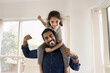 © fizkes - Little Indian kid boy looking at camera seated on young father shoulders, striking together playful strongman pose, showing off their arms muscles. Fatherhood, wellness, healthy and sportive lifestyle