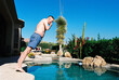 © Cara Dolan/Stocksy - Candid film photo of man doing bellyflop into backyard swimming pool