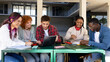 © Daniel - University students collaborating on project outdoors using laptop and notebooks