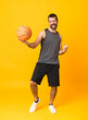 © luismolinero - Full-length shot of man over isolated yellow background playing basketball